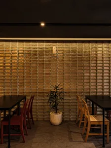 Dining area with tables and chairs, tile walls, a potted plant, and modern decor