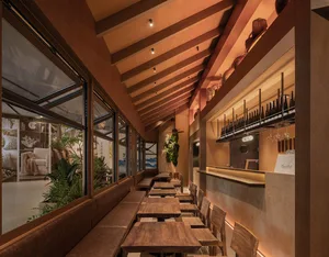 Cozy modern restaurant with wooden tables, chairs, and potted plants, creating a welcoming atmosphere