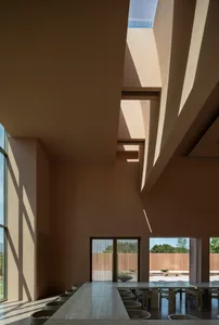 A large open space with high ceilings, a skylight, concrete walls, and two windows, giving a modern and industrial feel