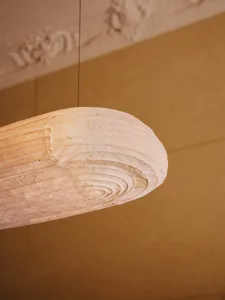 A simple room with a warm yellow tone and a unique wooden lamp resembling a shell or driftwood