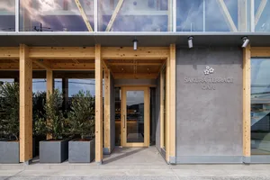Inviting restaurant entrance with a wooden doorway, potted plants, and a modern design