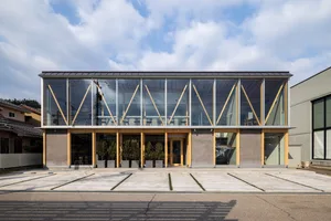 A modern building with a large glass wall and natural light, featuring potted plants and seating areas