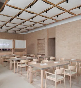 Modern restaurant interior with wooden walls and floors, multiple dining tables and chairs, and a warm inviting atmosphere