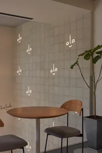 A well-lit dining area with two chairs and a wooden table, surrounded by potted plants and unique smiley face wall decor