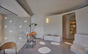 A clean and organized showroom featuring white seating options, a potted plant, and various furniture arrangements