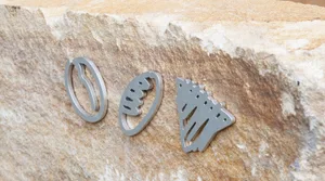Three metal sculptures resembling footballs, pizza slices, and a house are arranged on a rock surface, showcasing creativity and craftsmanship
