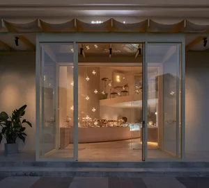 A clean and elegant jewelry store with white walls, vibrant jewelry on display, and potted plants, inviting customers to explore its fine offerings
