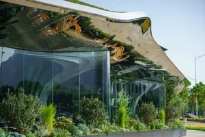 Modern building with glass walls, natural light, and potted plants, featuring a minimalist design with clean lines and simple shapes