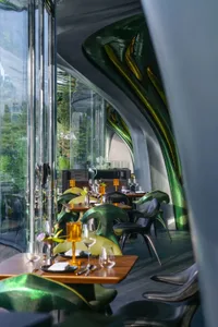 明亮吸引人的玻璃牆餐廳空間，配有多張餐桌、椅子和酒杯，為賓客準備好享用餐點