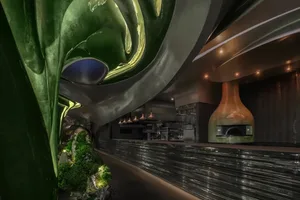Modern restaurant bar with black marble walls, potted plants, and a countertop