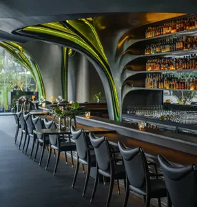 Modern bar lounge with a curved counter, wooden chairs, and wine glasses, creating an inviting atmosphere for socializing