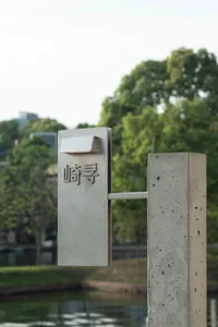 城市街角的大型混凝土結構，旁邊有金屬停車計時器與樹木，周圍環繞其他樹木