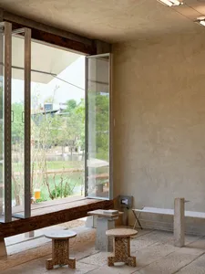 A serene living area with a wooden bench and dining table near a large window overlooking a waterway, with two chairs and a peaceful atmosphere
