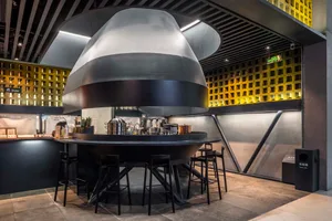 Modern restaurant interior with a large dome structure, black and silver finish, and potted plants, providing ample seating options