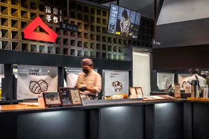 Casual Asian restaurant with a counter displaying food items, a TV on the wall, and two people in the scene