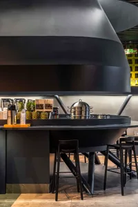 Cozy restaurant interior with a large wooden dining table, chairs, and potted plants