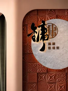 A well-lit Asian restaurant interior with a wall featuring Chinese characters and a tile pattern, creating a warm atmosphere