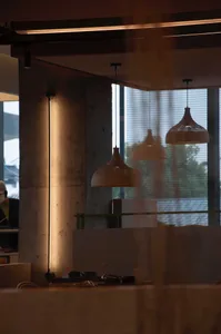 現代辦公空間內部景觀，混凝土牆面、木質元素與懸吊燈具提供照明