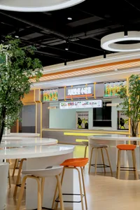A modern Asian restaurant with a large dining area featuring tables, chairs, and potted plants, creating an inviting and comfortable atmosphere
