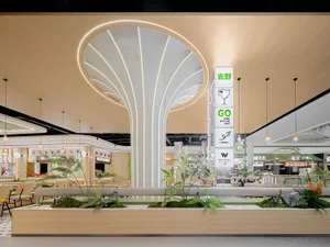 A restaurant interior with a central dome, surrounded by plants, chairs, and dining tables, creating a warm and inviting atmosphere