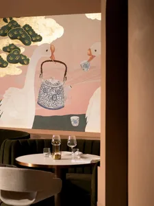 Dining area with a wooden table, chairs, wine glasses, a cup, and a vase, creating a cozy and inviting atmosphere