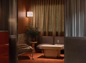 Cozy living room with a couch, chair, and table, featuring brown tones and wooden elements