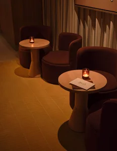 A well-lit restaurant dining area with three brown chairs around a table, a menu displayed, and warm lighting creating an inviting atmosphere