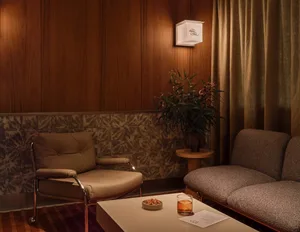 Cozy living area with two couches, chairs, a potted plant, and a decorative vase, creating a warm and inviting atmosphere