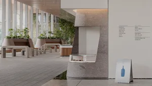 A modern building interior with a large stone wall, benches, and potted plants creating a welcoming atmosphere