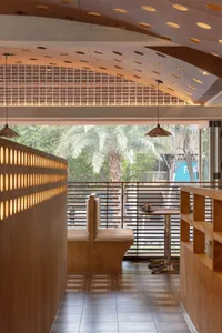 A restaurant interior with multiple tables, chairs, and potted plants, creating a welcoming atmosphere