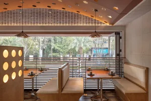 Warm and inviting restaurant interior with wooden floors, tables, chairs, and benches in various configurations