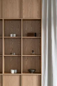 A wooden bookshelf filled with books, decorative objects, and bottles, creating a cozy and inviting atmosphere