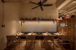 A cozy dining area with a wooden table and chairs, surrounded by cups and a warm atmosphere