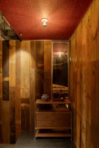 Warm and inviting interior space with a red accent wall, wooden surfaces, and natural elements like plants and a vase on a table