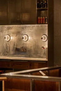 A clean and organized kitchen with a sink, two lights above it, and two bottles on the countertop