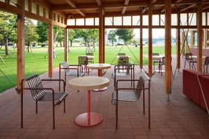 A round wooden dining table surrounded by several chairs in a comfortable outdoor patio setting