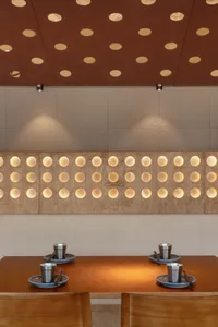 A modern space with a wall featuring rows of round circles, surrounded by decorative bowls, creating a stylish atmosphere