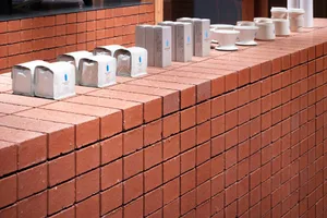 A brick wall with coffee cups, tea bags, and small boxes scattered across it, creating a casual and relaxed display