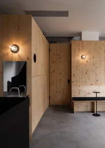 Modern bathroom with wooden walls and floors, featuring two sinks and a bench in a clean and well-organized space