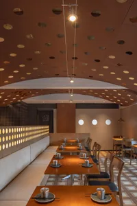 A warm and inviting dining space with multiple tables and chairs, featuring several bowls and a comfortable atmosphere