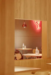 Warm and inviting restaurant interior with wooden walls and tables, featuring chairs and bottles, creating a cozy atmosphere