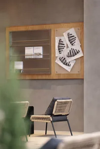 A cozy living space with a woven chair, a wooden couch, and two books, suggesting a warm and inviting atmosphere