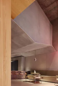 Modern restaurant interior with concrete walls, dining tables, and chairs, creating a stylish and inviting atmosphere