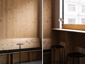 A well-lit dining space with wooden and black elements, featuring a dining table and chairs, with a comfortable atmosphere