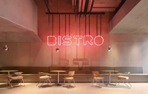 現代餐廳內部，設有多張餐桌椅、紅色霓虹燈寫著 bistro，以及時尚氛圍