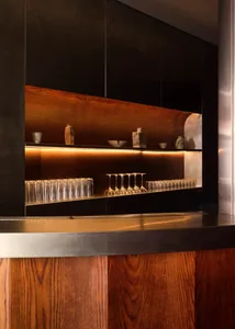 A bar area with a wooden countertop featuring various glasses and bowls, creating a cozy and inviting space for socializing