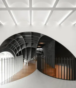 Open modern space with a curved wall, chairs, and a minimalist atmosphere