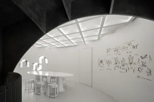 Empty white room with a curved wall, chairs, and a dining table, creating a clean and minimalistic atmosphere