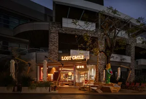 Cozy outdoor dining space with tables, chairs, umbrellas, and a mix of wood and metal materials under warm lighting