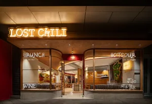 Warm restaurant entrance with a wooden facade, well-lit interior, and comfortable seating areas